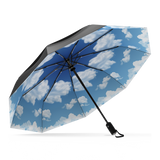 The Blue Sky Top Best-Selling Windproof Compact Travel Umbrella is pictured on it's own, open and leaning to the left. The Canopy is black and the interior shows off the blue sky motif.