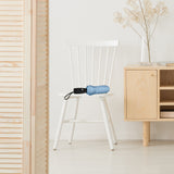 Neutral-colored room with a closed light blue travel umbrella resting on a chair.