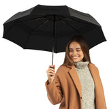 Photo of a woman carrying an open black travel umbrella