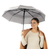 Woman holding Repel's best-selling windproof gray travel compact umbrella. 